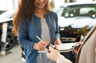 DirectAsia Insurance_A female holding a pen, signing papers and another person waiting to pass the car key to her